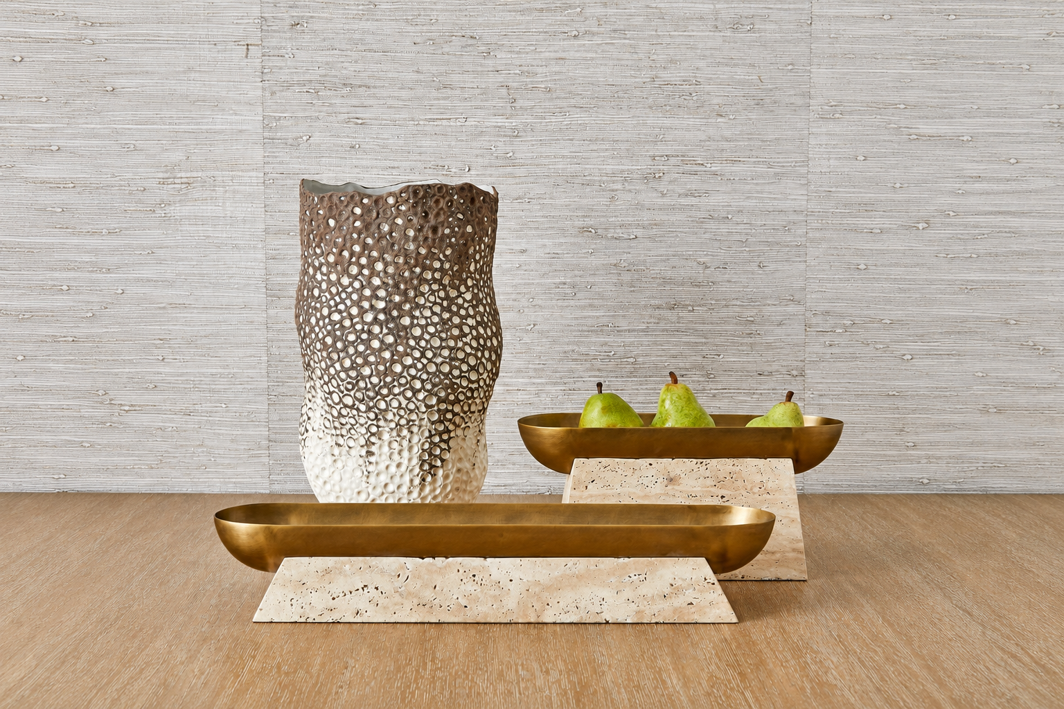 Brass bowls on stone bases beside a textured metallic vase